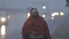 အူတာပရာဒက်ရှ်ပြည်နယ်က လမ်းမပေါ်မှာ ခြုံစောင် ခြုံထားတဲ့ အမျိုးသမီးတစ်ဦး လမ်းလျှောက်လာပုံ၊ မြူတွေဖုံးနေတာကြောင့် နောက်ခံမြင်ကွင်းက ကားမီးရောင်တွေကို မှုန်ဝါးဝါးသာ မြင်ရ