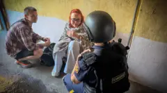 Люди сидять на землі, загорнуті у ковдри 