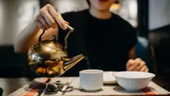 Una mujer echa agua caliente en una taza 