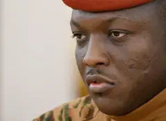 Portrait gros plan du Capitaine Ibrahim Traoré, il porte une tenue militaire et un béret rouge sur la tête