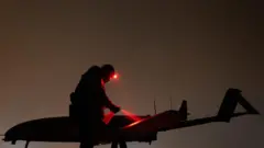 Украинский дрон самолетного типа на земле и силуэт человека в темноте (архивное фото)