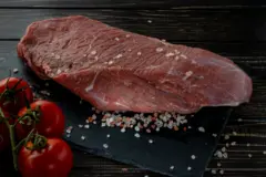 Filete de carne cruda con especias sobre un fondo de pizarra oscura, piedra u hormigón.