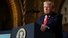 O presidente dos Estados Unidos, Donald Trump, em fala pública em sua propriedade em Mar-a-Lago, em 22 de dezembro de 2025. Ele usa terno e gravata e olha de forma séria para a frente.