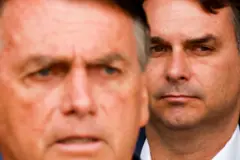 Imagem do rosto de Jair Bolsonaro levemente desfocado em primeiro plano, com rosto de Flávio focado, ao seu lado, um pouco atrás