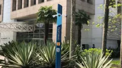 Poste azul da empresa CoSecurity instaladoroleta verticalfrente a prédio