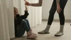 Dete sedi na podu dok ga starija osoba grdi
