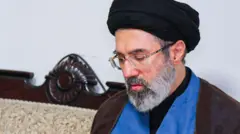 Mojtaba Khamenei wé láwàní dúdú sórí, ó wọ ìgò ojú, ó ń wo ilẹ̀