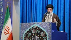 Jamenei con barba blanca y una bandera de Irán en un discurso.