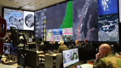 Varios militares en una sala con pantallas gigantes que muestran el mapa de Noruega.