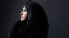 نیم رخ مرجان ساتراپی با لباس سیاه، پسزمینه تصویر سیاه است