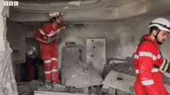 破壊されたテヘランのビルの中で作業する赤新月社の救急隊員