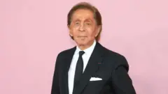 Valentino Garavani compareceu à cerimônia de entrega dos prêmios CFDA de 2019 no Museu do Brooklyn, em Nova York, no dia 3 de junho de 2019, vestindo um terno preto e posando contra um fundo rosa.