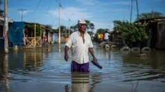 Homem caminha com água acima dos joelhos durante uma inundação causada pelo El Niño no Peru