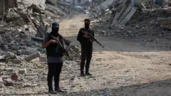 Combatientes de Hamás armados en una calle con escombros