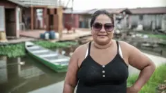 Mulher pescadora diantesociedade esportiva palmeiras vs santos futebol clubecasas e uma canoa flutuando sobre água 