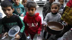 أطفال في غزة ينتظرون ملء أوانيهم الفارغة بالطعام 