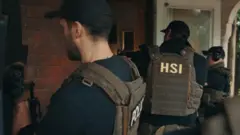 Policiais em ação na porta de uma casa.