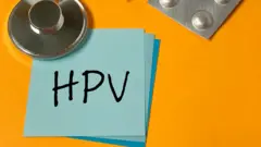 Sarı bir fon üzerine yapıştırılmış mavi bir not kağıdında 'HPV' yazıyor. Hemen üzerinde ilaç kutusunun bir kısmı görülüyor. 