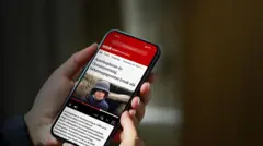 Egy kézben tartott telefonon a BBC News Magyarul egyik cikke olvasható.