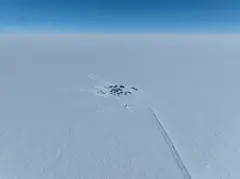 Um pequeno grupo de tendas e abrigos temporários no meio do gelo branco da Antártida em um dia de céu azul ensolarado