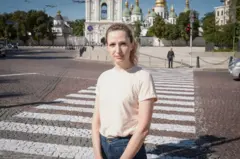 Maria Drachova, con jeans y camiseta de manga corta, posa ante la cámara al lado de un cruce de peatones en una calle de Ucrania