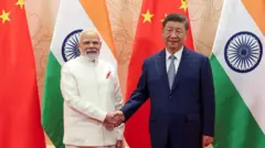 Umushikiranganji wa mbere Narendra Modi na prezida Xi Jinping bahanye ukuboko imbere y'amabendera y'ibihugu vyabo. Modi yambaye kostime ya beje nawe Xi yambaye kostime y'ubururu n'ikaruvato y'ubururu ikeye n'ishati yera. 