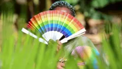 Umugore muri Uganda ufite icyapa cy'amabara y'umukororombyi aranga abatinganyi