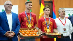 Četiri muškarca, jedan u plavom odelu, u sredini dvojica u dresu španske reprezentacije i medaljama oko vrata i na kraju stariji čovek u beloj košulji