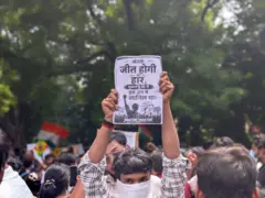 प्लेकार्ड लिए एक प्रदर्शनकारी