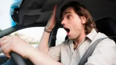 Homem faz um gesto de quem esqueceu alguma coisa enquanto dirige um carro