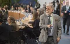 Celso Amorim usando terno cinza e credenciais durante evento num salão onde foi realizado o G20