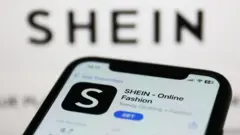 Imagem mostra aplicativo da Shein em celular e logo da marca chinesa ao fundo da imagem