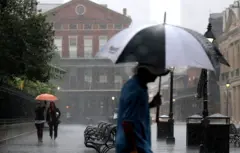 Vecinos de New Orleans caminan bajo una intensa lluvia en 2017.