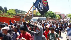 يحمل أحد المتظاهرين لافتة عليها نسخة مدغشقرية من شعار المانغا اليابانية الشهيرة ون بيس، وهو رمز تبنته حركات الاحتجاج بين جيل زد في جميع أنحاء العالم، بينما يسير مع متظاهرين آخرين خلال مظاهرة وطنية بقيادة الشباب احتجاجًا على انقطاع التيار الكهربائي المتكرر ونقص المياه، في أنتاناناريفو، مدغشقر، 13 أكتوبر/تشرين الأول 2025.