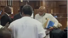 Nnamdi Kanu ree laaarin awọn eeyan pẹlu iwe gbangba lọwọ ni kootu. O wọṣọ funfun to bo ara rẹ de ibi ọrun, o fa ori rẹ dan.