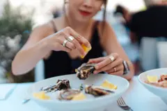 A woman squeezes lemon on an oyster