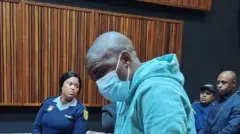 Nkosinathi Phakathi yambaye agapfukamunwa n'imyenda y'imyitozo y'ibara ry'ubururu, ubwo yakatirwaga n'urukiko rukuru rw'i Johannesburg, muri Afurika y'Epfo, ku itariki ya 4 Ukwakira (10) mu mwaka wa 2024