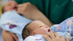 أطباء يعتنون بمواليد جدد في مستشفى في يوم رأس السنة الجديدة، 1 يناير/كانون الثاني 2025، بمقاطعة يوبينغ دونغ ذاتية الحكم، مدينة تونغرن، مقاطعة قويتشو، الصين. 