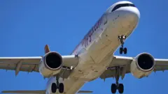 İniş takımları açık bir Pegasus A320 uçağı Barcelona'ya inerken alttan görüntülenmiş