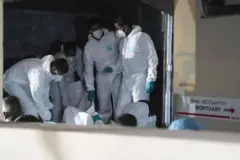 Varios hombres vestidos con trajes mueve protectoresn cuerpos recuperados del buque iraní hundido