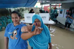 Dua warga di Desa Tanjung Gusta, Deli Serdang, Sumatra Utara menunjukkan jari bertinta yang menandakan mereka  mengikuti pilkada serentak pada November 2024 di tengah kepungan banjir.