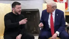 Zelensky e Trump sentados em salão, gesticulando e falando