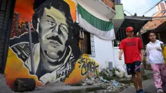 Niños caminando junto a un mural de Pablo Escobar en Medellín en 2023.