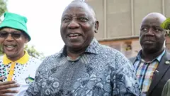 Le Président Cyril Ramaphosa, tout souriant avec deux de ses collaborateurs
