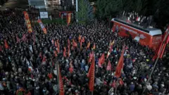 CHP otobüsünün tepesinde liderler var, yukadıdan çekilen fotoğrafta bayraklar ve geniş bir kitle görünüyor. 