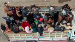 تُظهر هذه الصورة الجوية إجلاء أفراد من المجتمع البدوي على متن شاحنة تسير على طريق في بلدة الطارة، بمحافظة السويداء جنوب سوريا، في طريقها إلى درعا، في 21 يوليو/تموز 2025. 