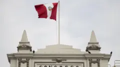 The Peruvian flag flies over the main façade of the Peruvian Congress.