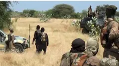 Awọn ọmọ ogun Boko Haram ati ISWAP ti wọn asọ ologun alawọ eweko duro ni ori asalẹ kan, maa woju ara wọn. Ọkọ akẹru kan wa nibẹ ati ọkọ ijagun kan naa duro. awọn mejeeji yii ni wọn kun ni ọda idamọ ologun tii se awọ eweko
