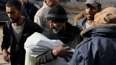 رجل يحمل جثة ابنه في غزة