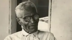 Foto em preto e branco de um homem negro usando óculos